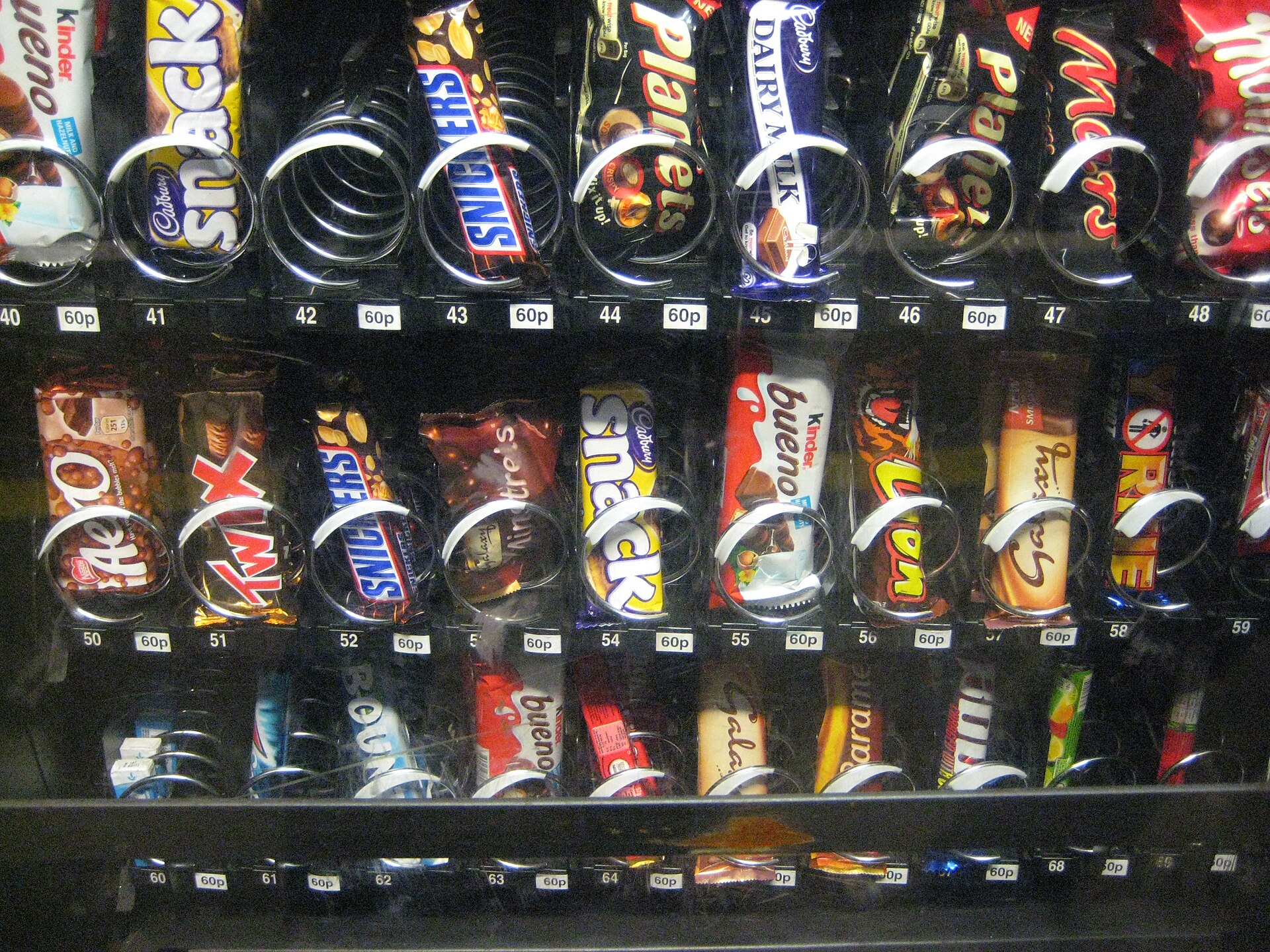 Close-up of a glass-front snack machine stocked with packaged snacks